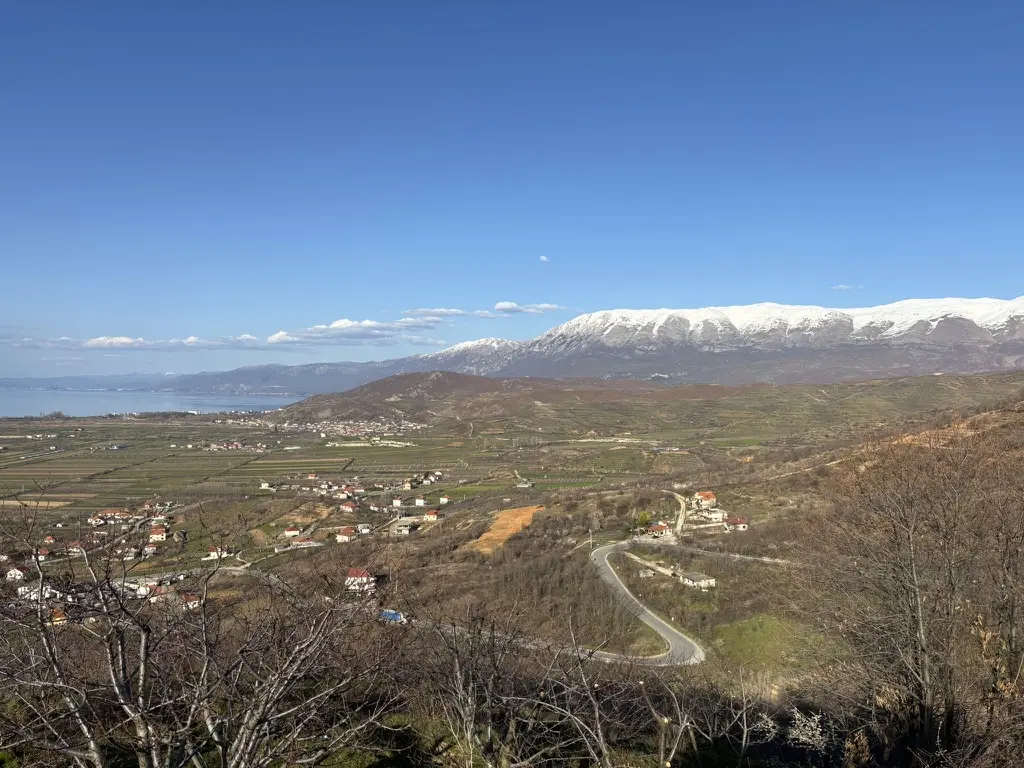 Snow-covered Albanian mountains rising beyond a broad valley
